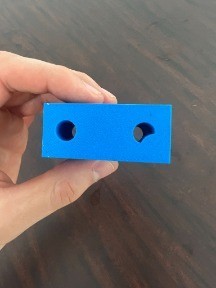 Printed end block held to the camera showing its two bored holes