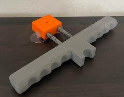 Finished shooter with gray body, finger grips, orange plunger head on springs, and suction feet