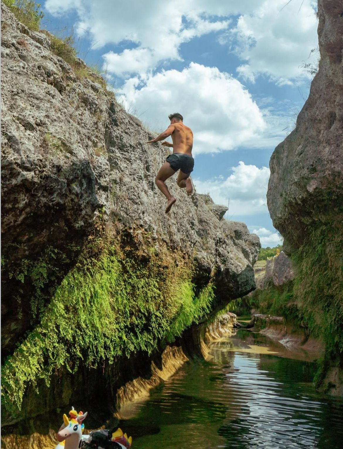 Leaping off a mossy cliff into the water below